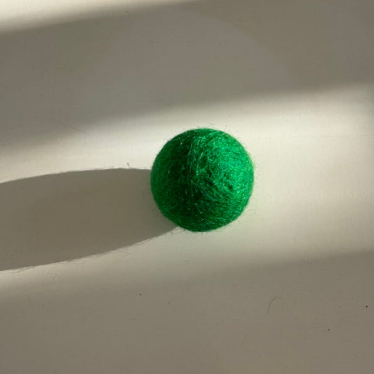 Green textured ball on a white surface with shadows
